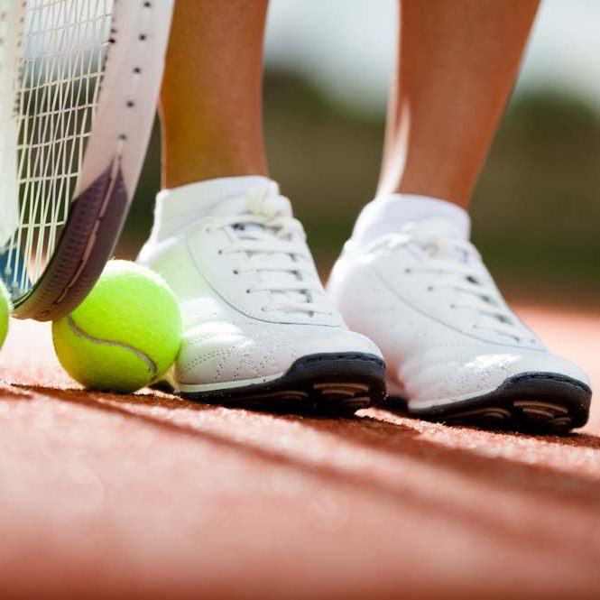 Legs of athlete near the tennis racket and balls